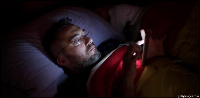 muž se dívá na telefon před spaním