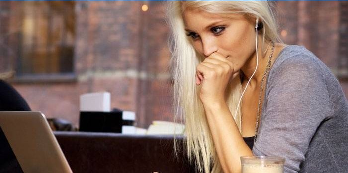 Dívka sedící u notebooku ve sluchátkách