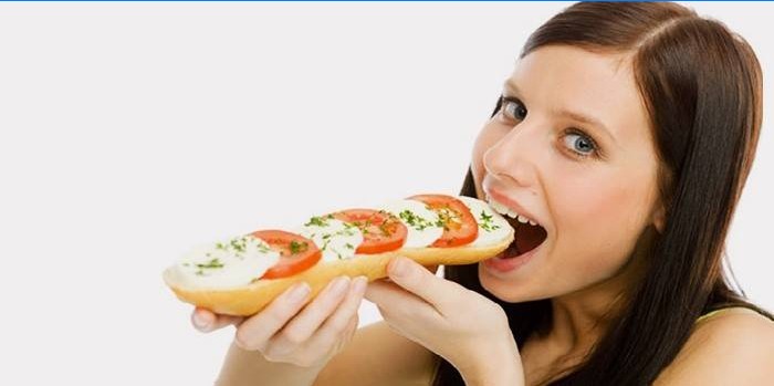 Dívka jí sendvič s rajčaty a sýrem