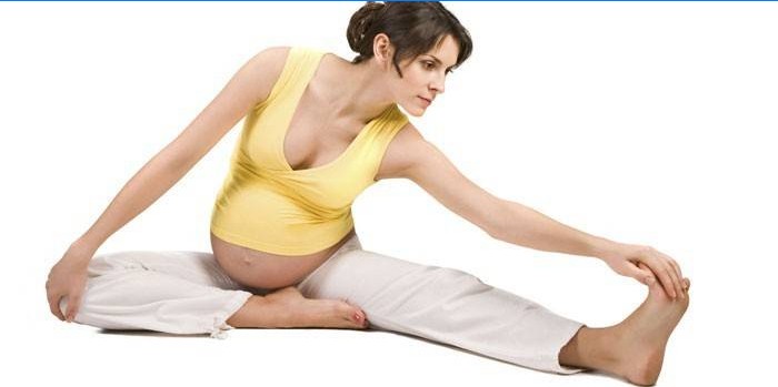 Těhotná dívka dělá protahovací cvičení