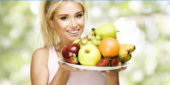Dívka drží misku s ovocem a ovocem.