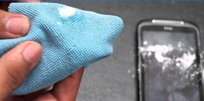 Hadřík s látkou v ruce a smartphone na stole