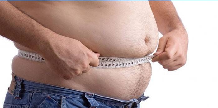 Muž měří objem břicha centimetrem