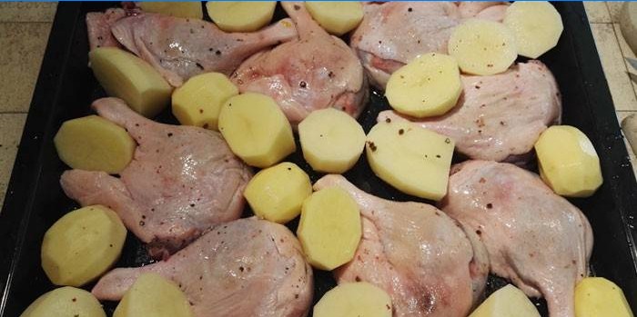 Kachní stehýnka s bramborami na plech před pečením