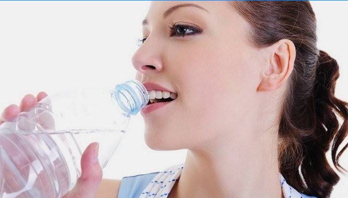 Dívka pije vodu pro hubnutí.