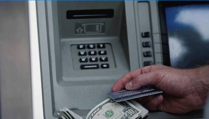 Muž dostává peníze na bankomatu