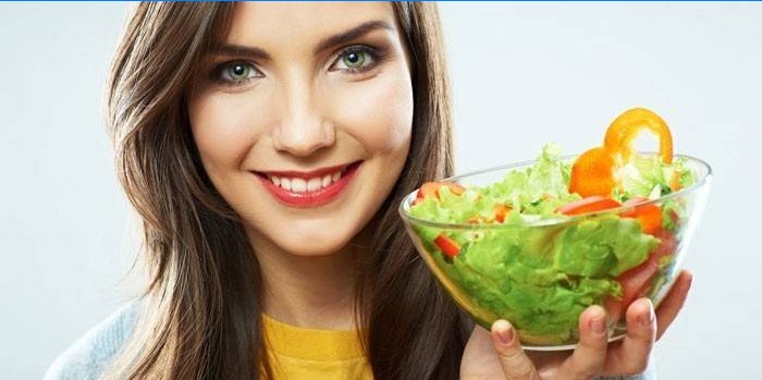 Dívka drží talíř se salátem v ruce