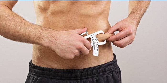 Muž měří procento tuku posuvným měřítkem