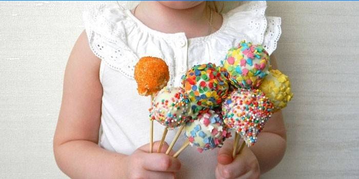 Dívka drží dort pop s barevnými postřikovačů