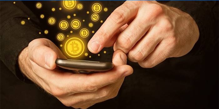 Muž s smartphone v ruce a bitcoinové ikony.