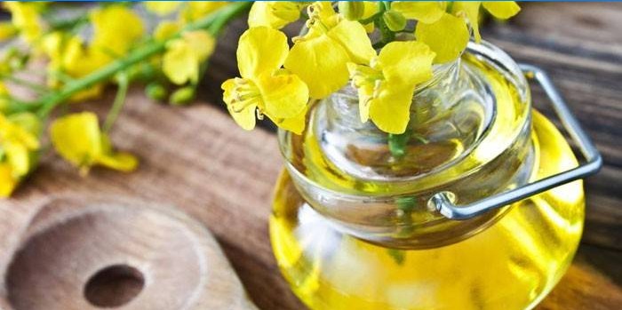 Řepkový olej ve sklenici a řepkové květy