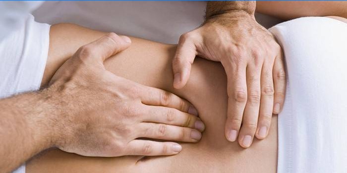 Člověk dělá masáž vnitřních orgánů břicha