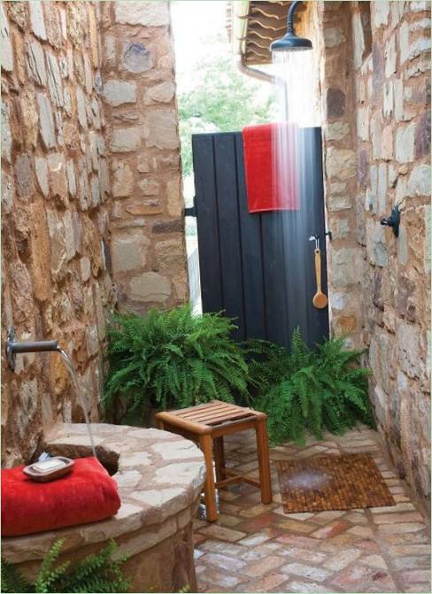 Sprcha s kamennými stěnami a dřevěnými dveřmi