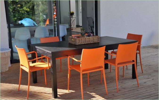 Černý jídelní stůl s jasně oranžovými židlemi