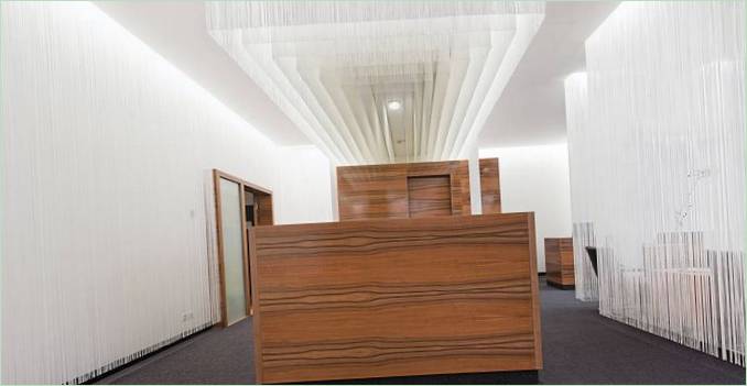Letištní hala: kaskádové svítidlo nad dřevěným recepčním pultem